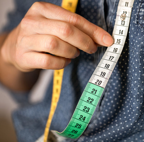 Main de couturière et mètre de couture